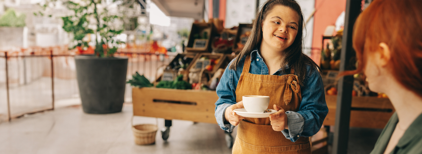 Smiling woman in apron holding a cup and saucer