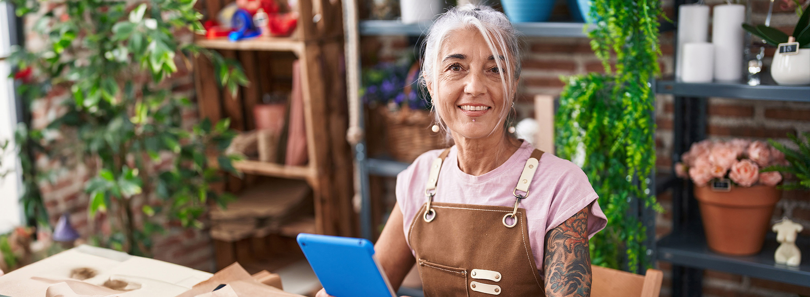 older woman wearing an apron smiling behind a cash register